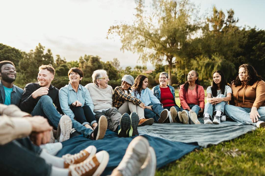 Diverse group of people sitting together outdoors, laughing and connecting